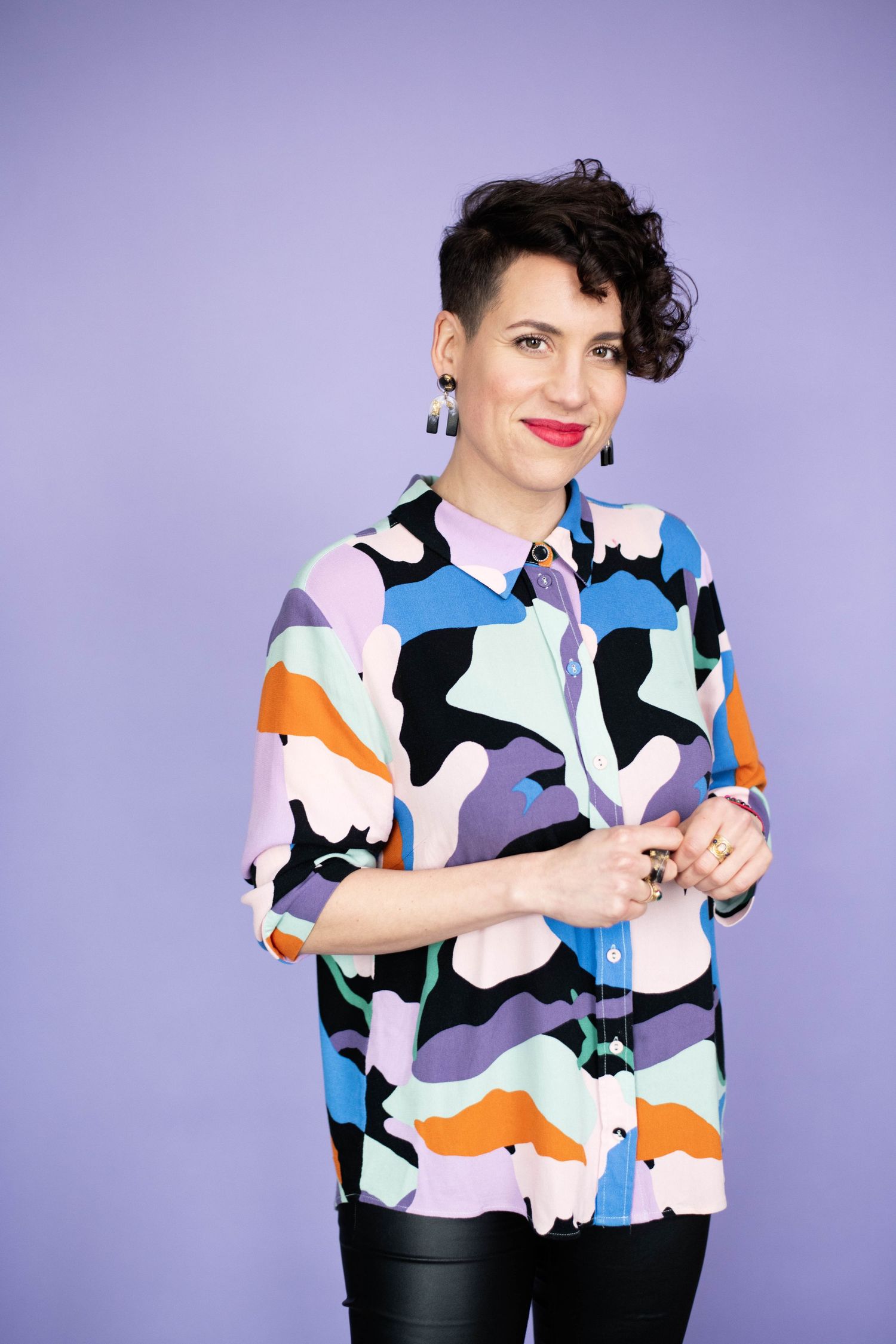 Fashion portrait on tan leather couch wearing gold and black patterned outfit.