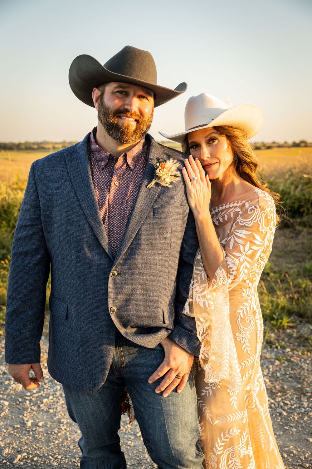 Country wedding couple in cowboy hat and lace dress pose during golden hour.