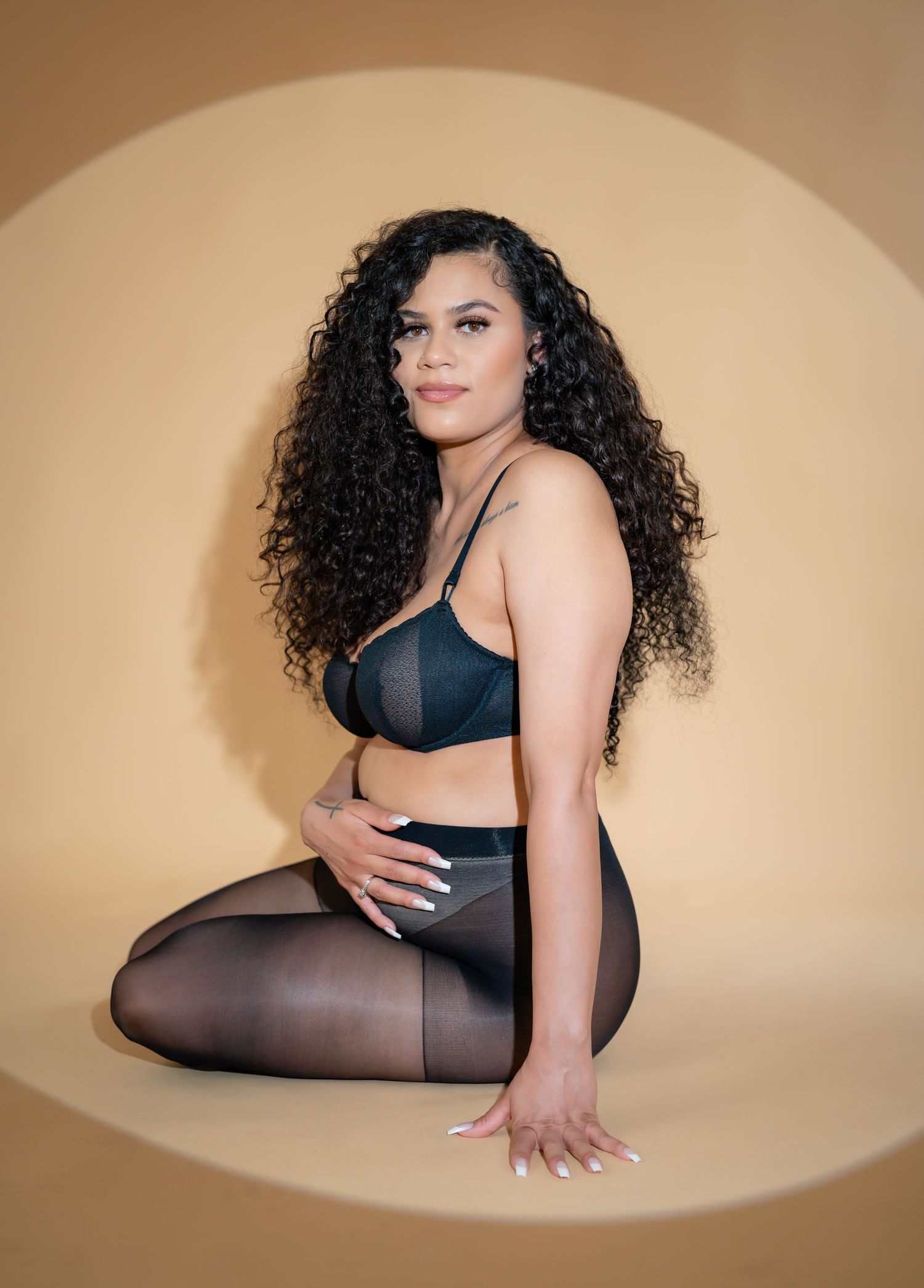 Artistic maternity photoshoot on beige background with dramatic lighting.