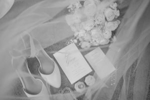 Wedding details flatlay with bridal shoes, invitation and white flowers.