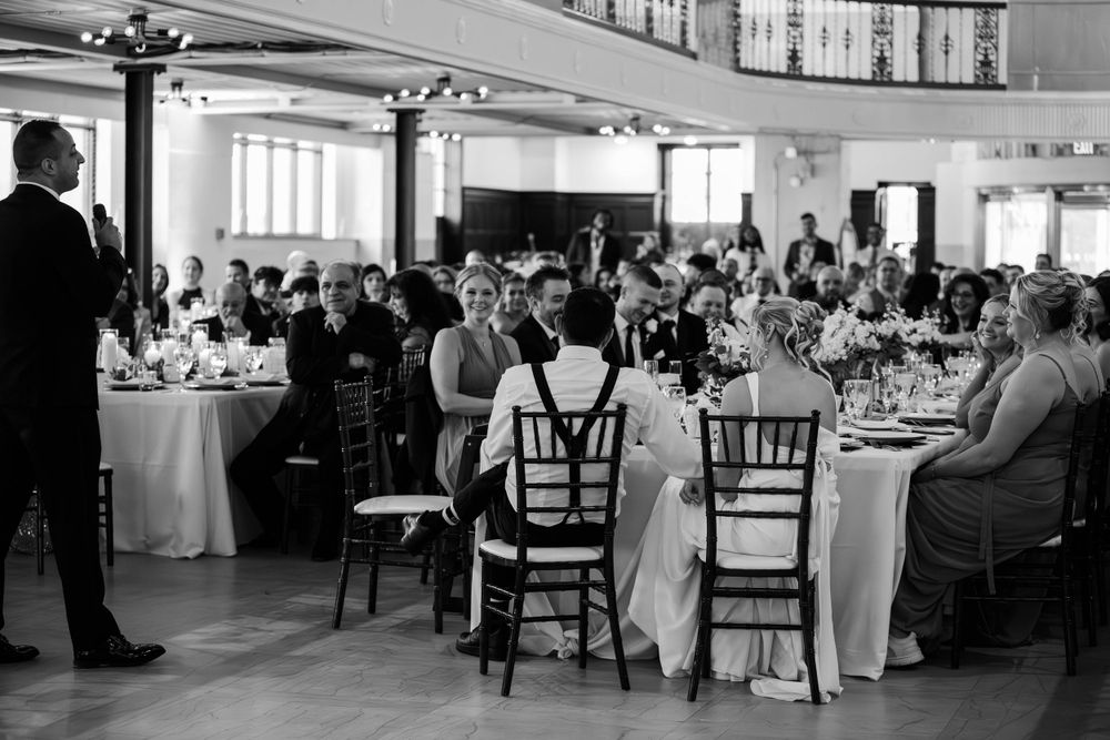 Wedding reception hall filled with guests at round tables in a classic black and white setting.