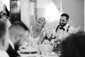 Black and white candid photo of guests laughing joyfully at wedding reception.