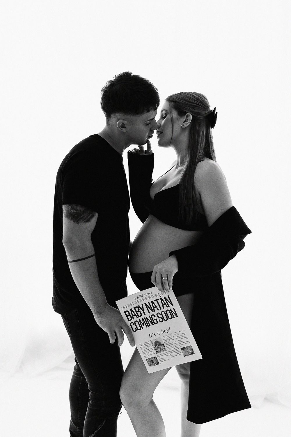 A black and white maternity photo featuring a couple sharing an intimate moment.