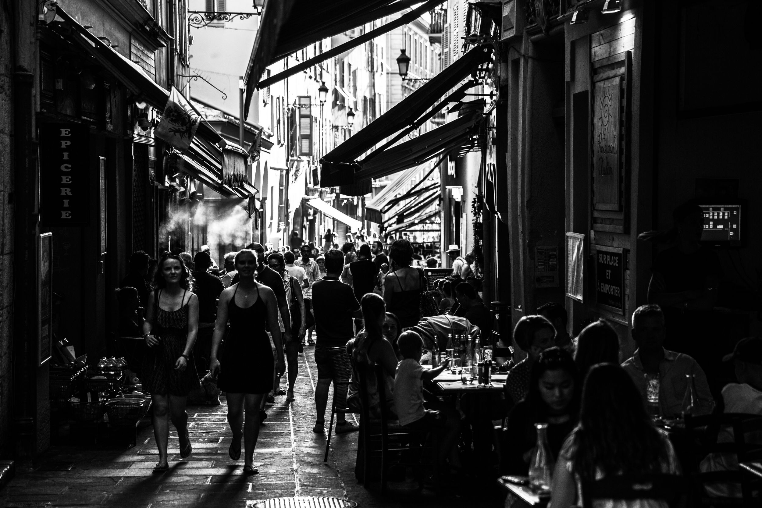 Atmospheric black and white photograph of a narrow cobblestone street with historic buildings.