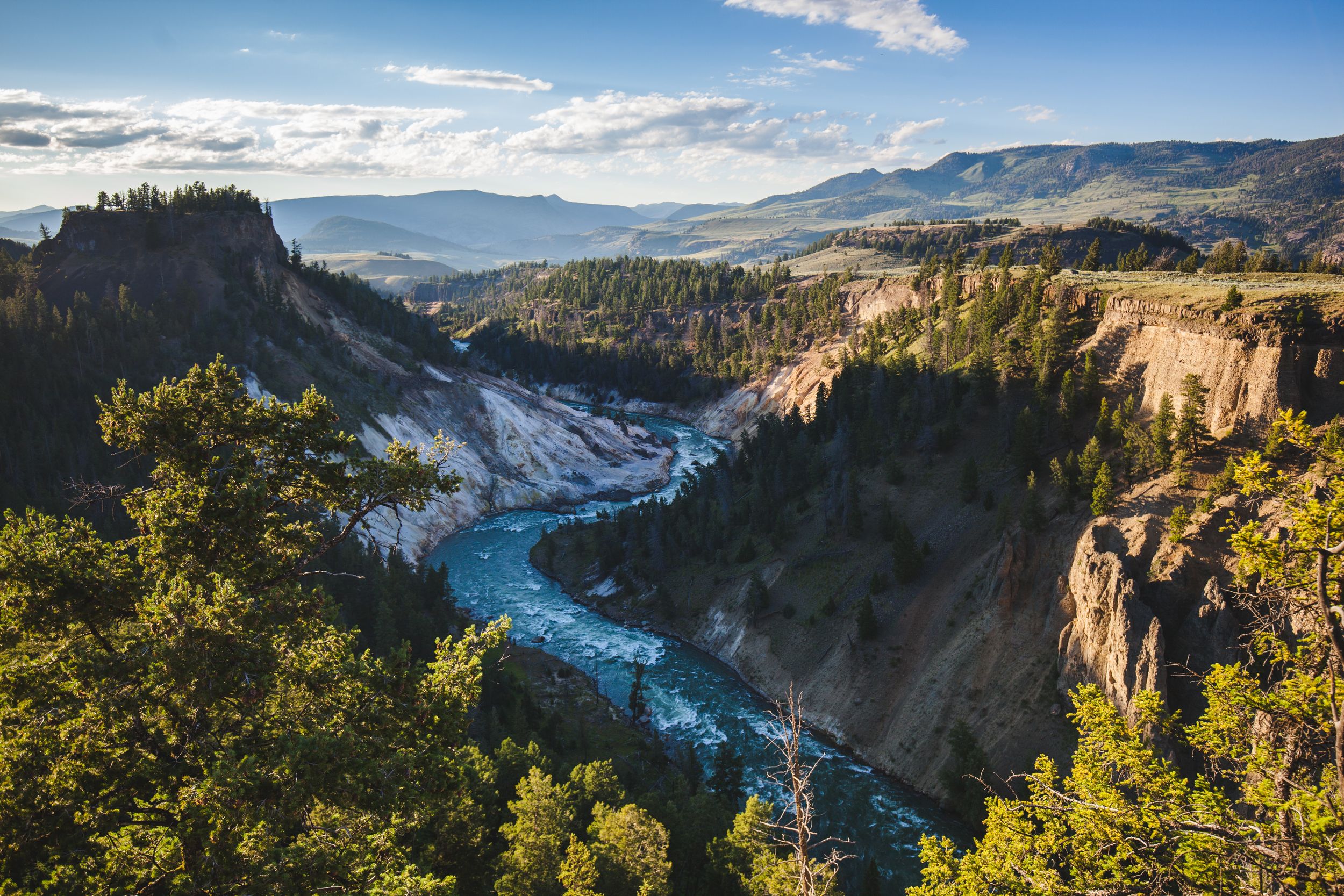 Dramatic canyon landscape with winding river and towering cliffs in golden afternoon light.