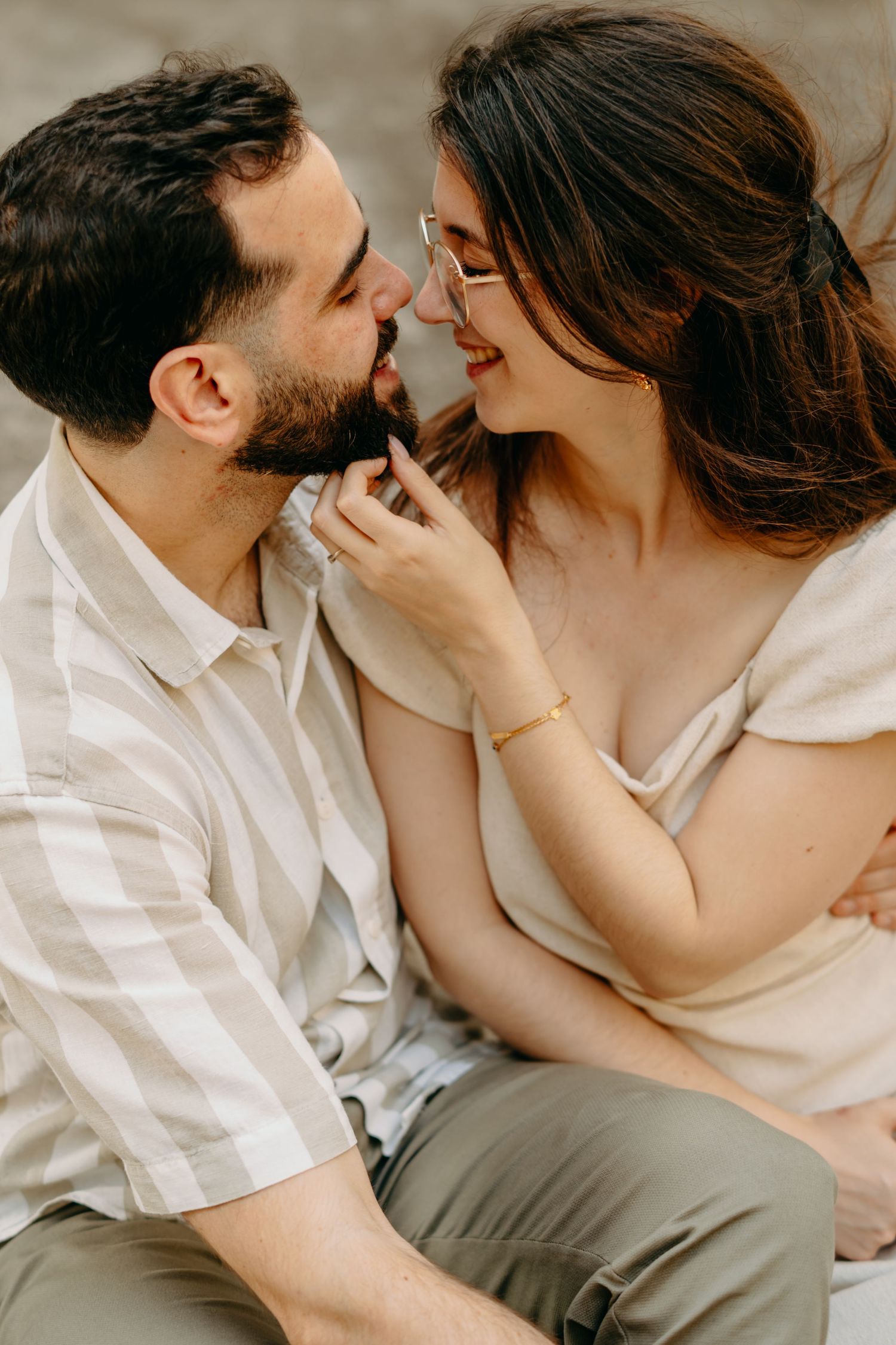 A romantic moment between a couple in neutral-toned clothing as they share an intimate close-up moment together.