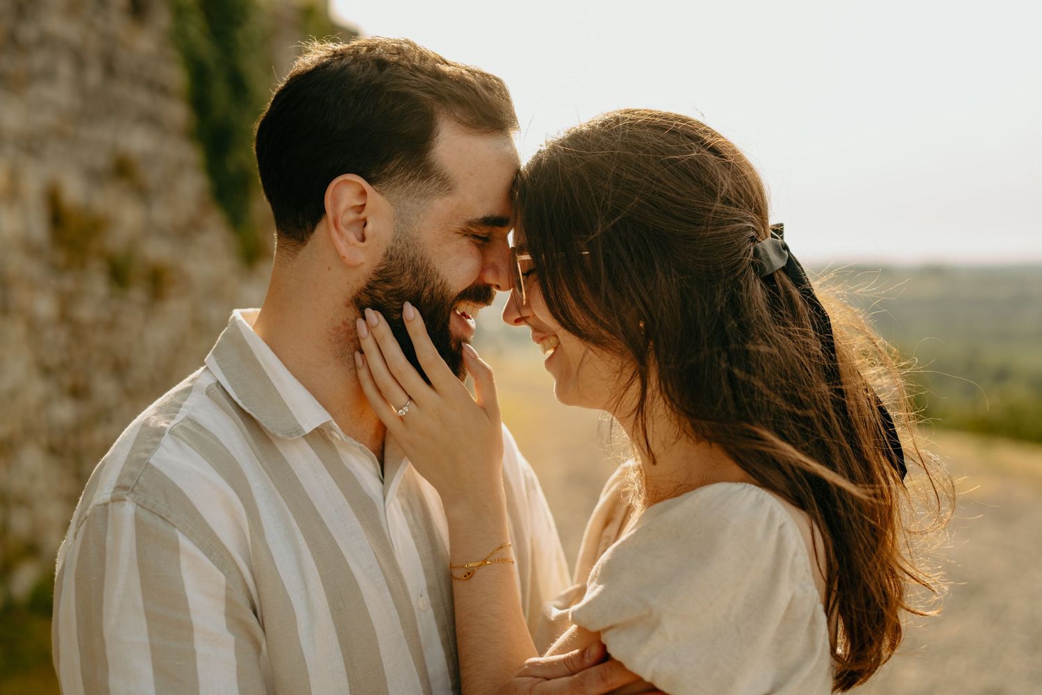 Romantic couple sharing an intimate moment at sunset in a rustic outdoor setting with warm golden light.