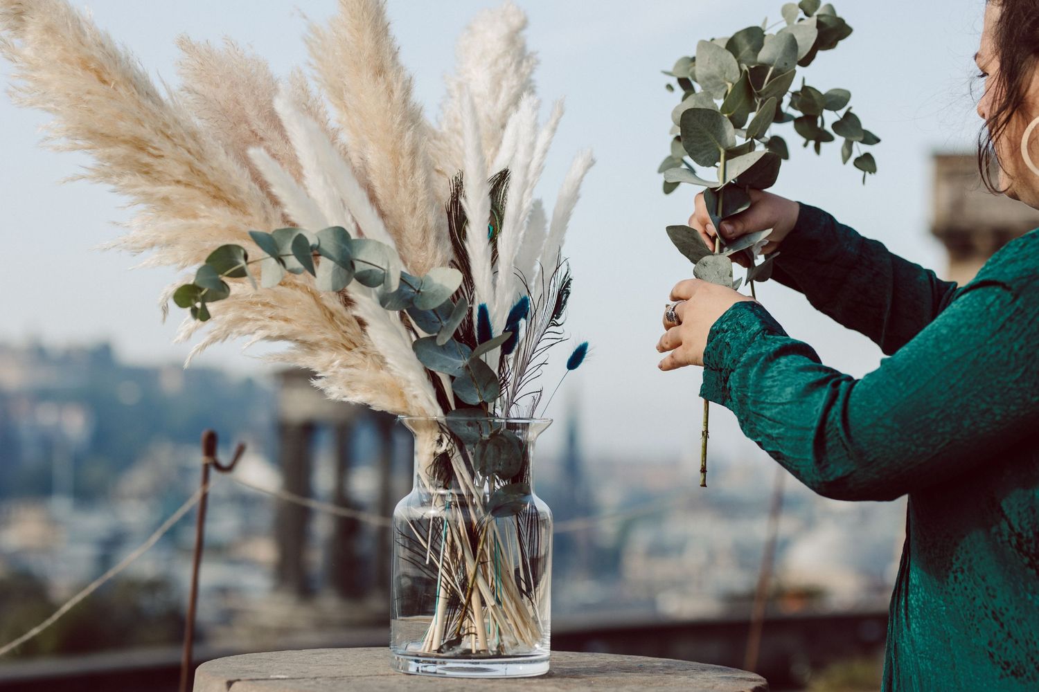 Pampas grass and floral arrangements in glass vases against a bright sky.