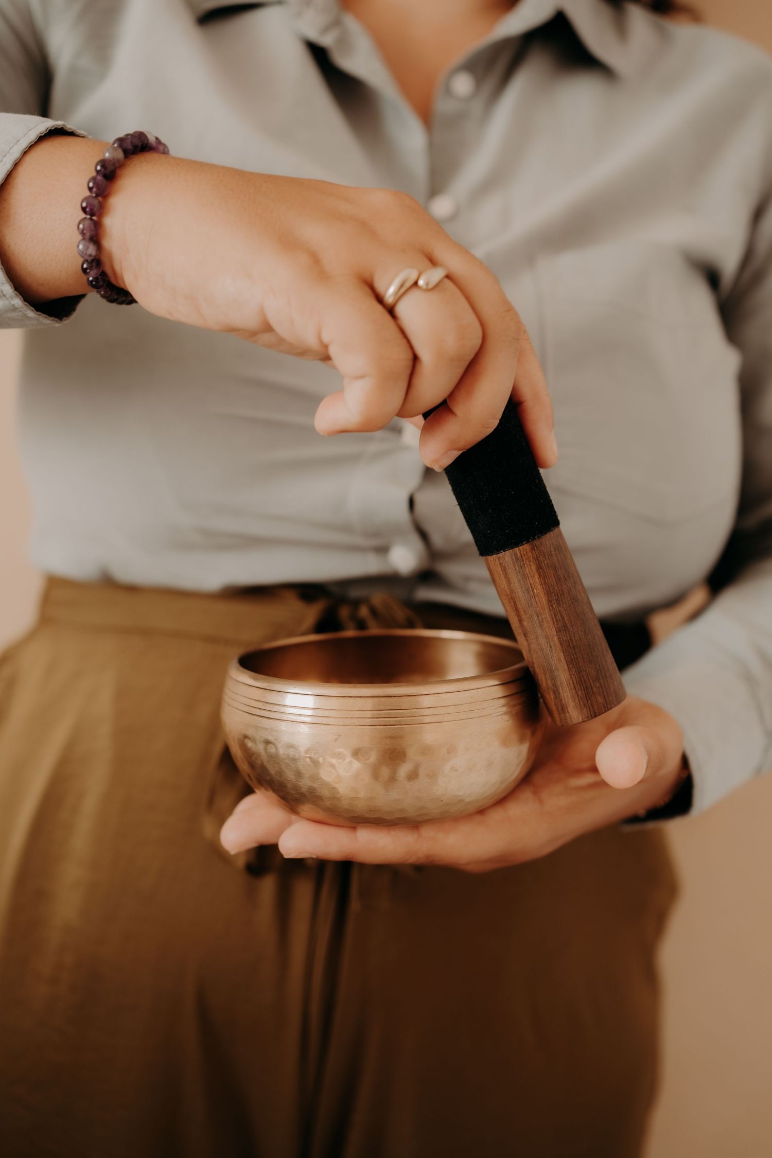 Hands holding and demonstrating use of a traditional singing bowl for sound therapy.
