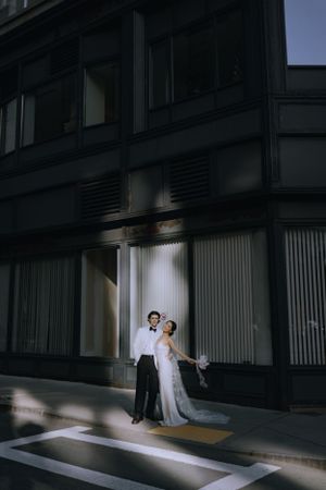 Minimalist wedding portrait in an urban setting with dramatic shadows and lighting.