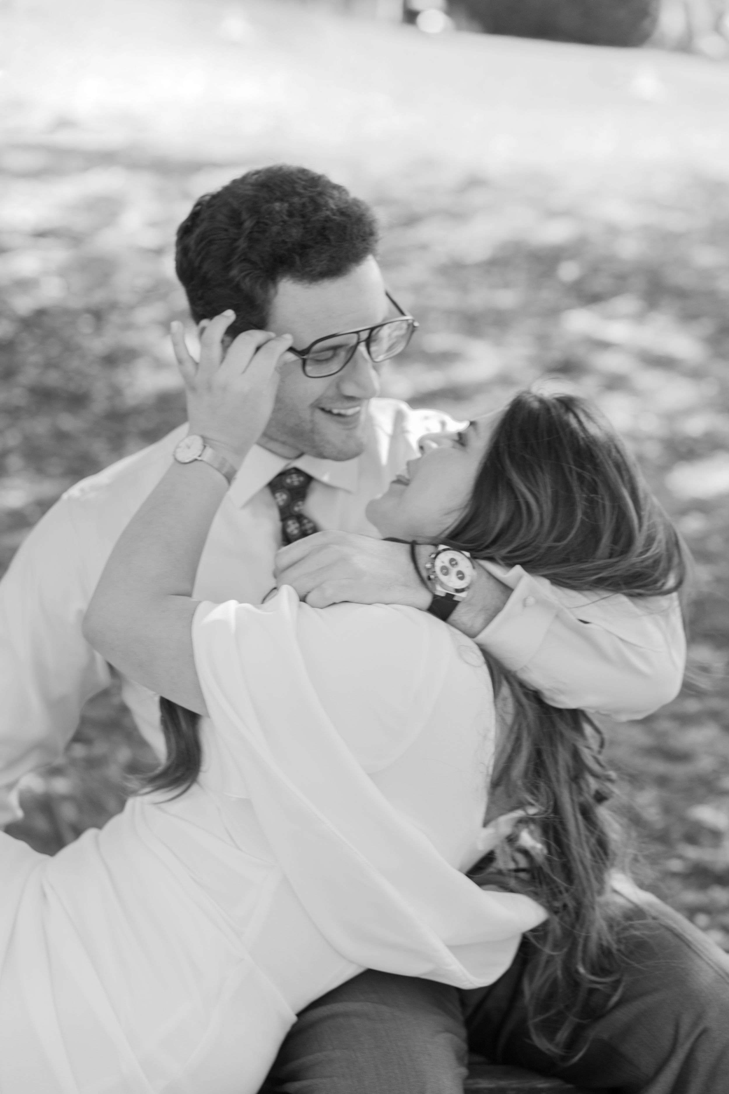 Black and white photo of a romantic moment shared between a couple in casual attire outdoors.