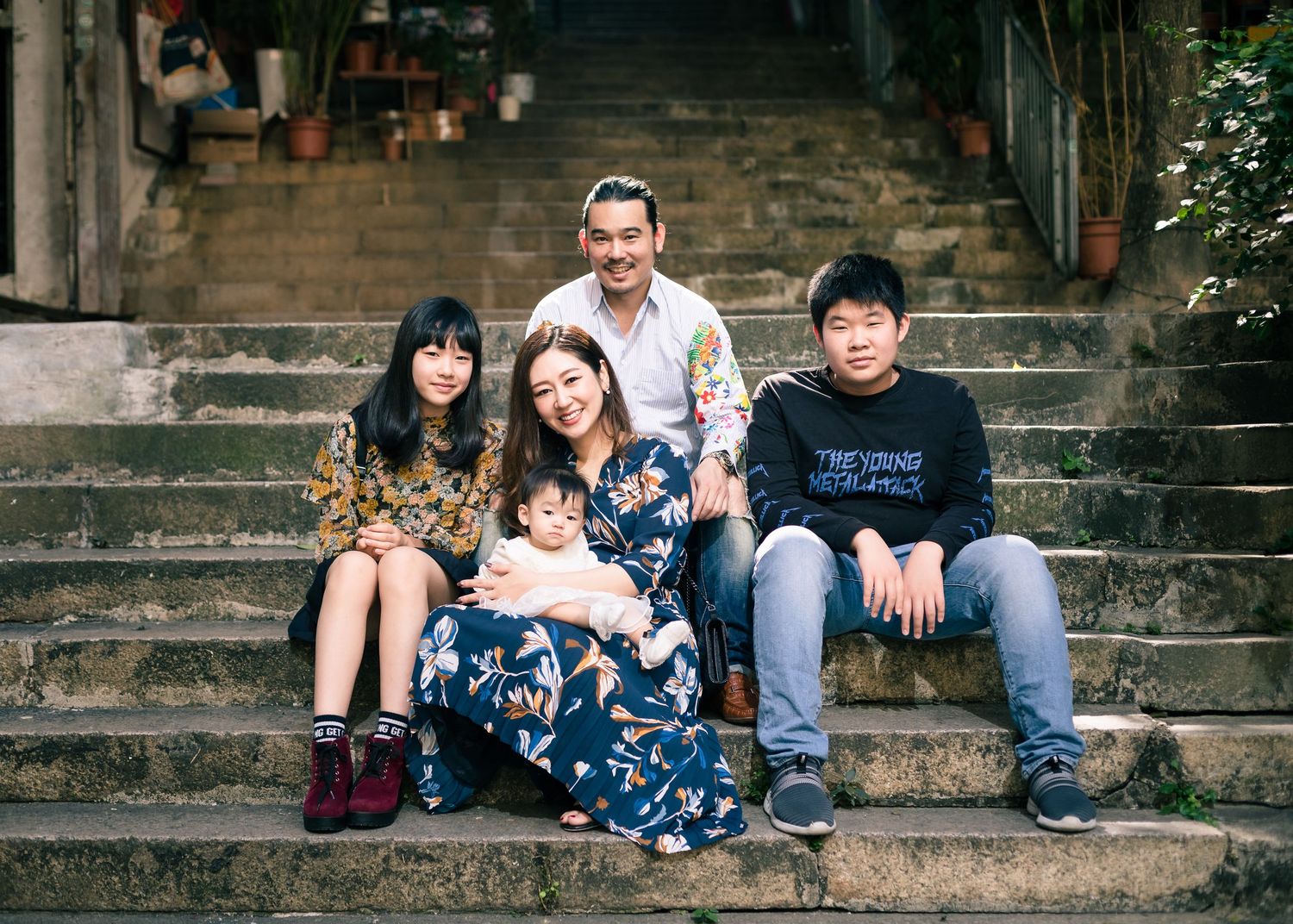 A family group portrait taken on stone steps in an urban alleyway setting.