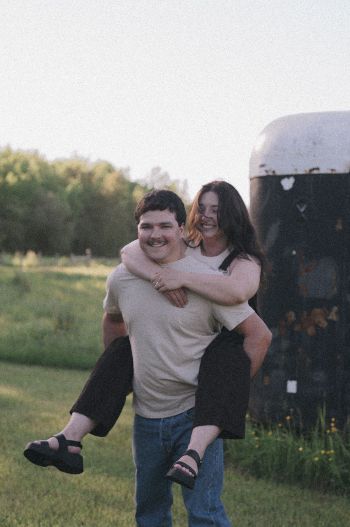 Playful piggyback ride in casual outdoor setting at sunset.