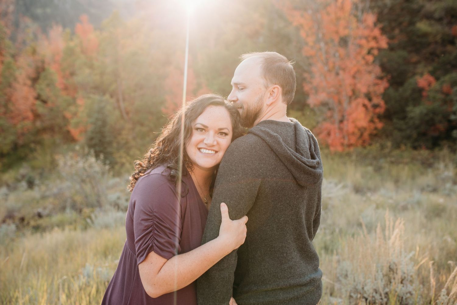 Romantic outdoor portrait with warm sunset lighting and autumn foliage creating a beautiful backdrop.
