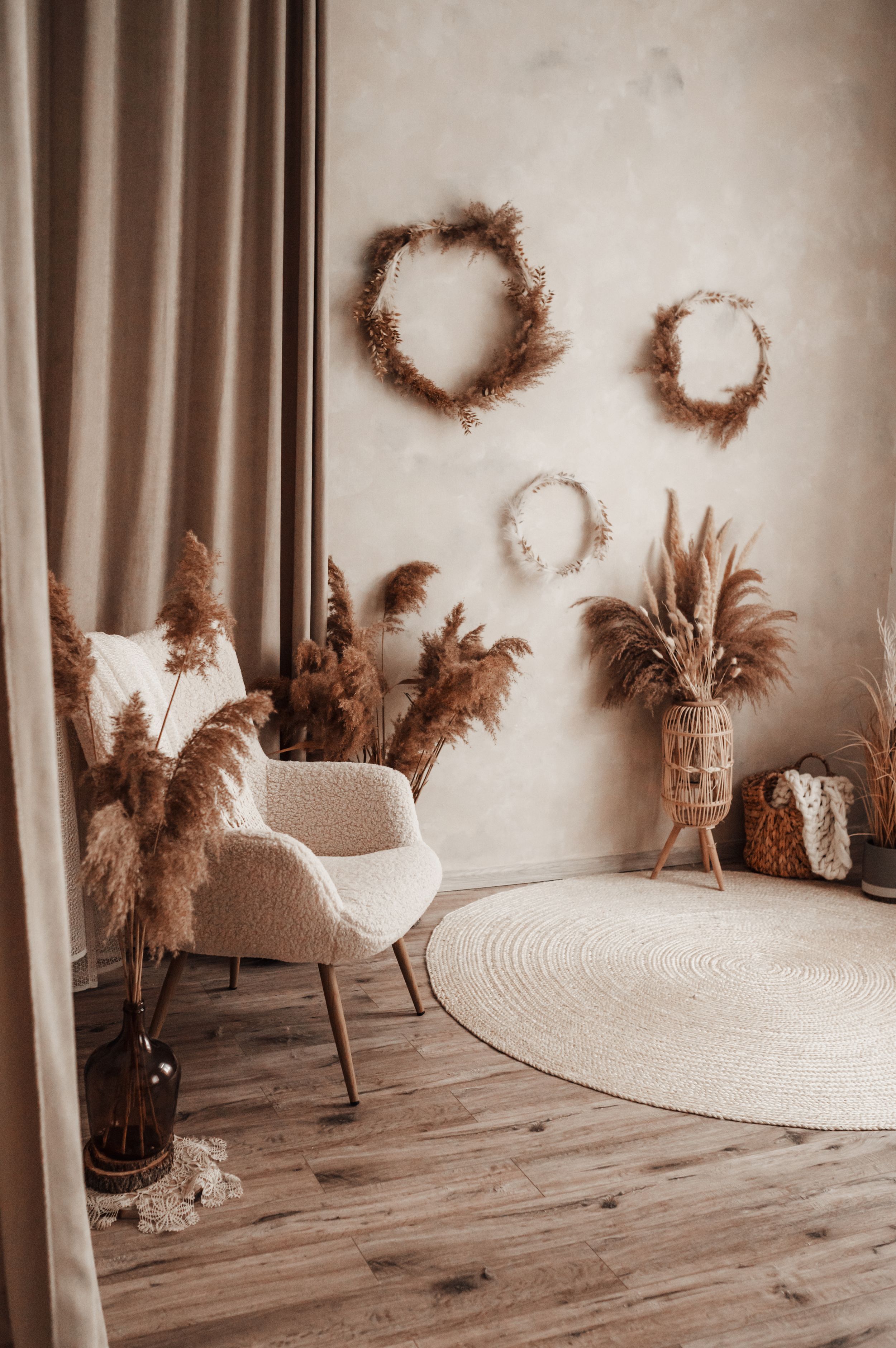 Modern boho room featuring circular wall wreaths, white accent chair, and round jute rug.