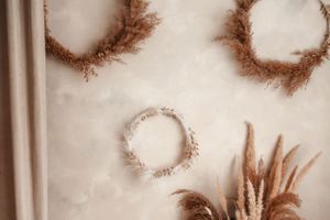 Close-up of dried floral wreaths on beige wall with pampas grass arrangement.