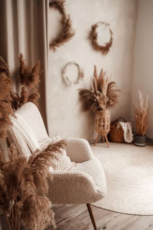 Cozy seating area with plush white chair, dried pampas grass, and decorative wall wreaths.