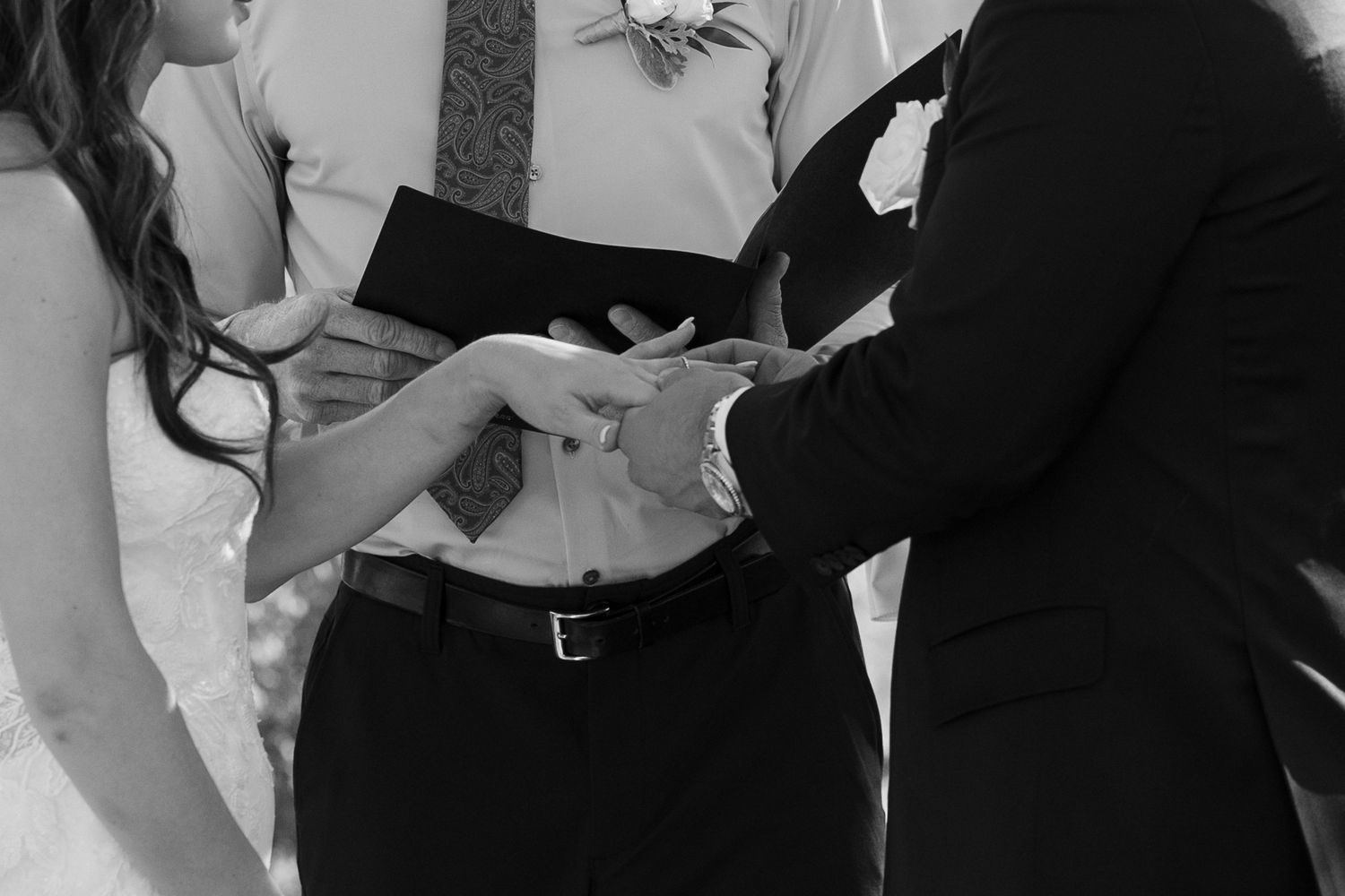 Black and white photo capturing a ring exchange during a wedding ceremony.