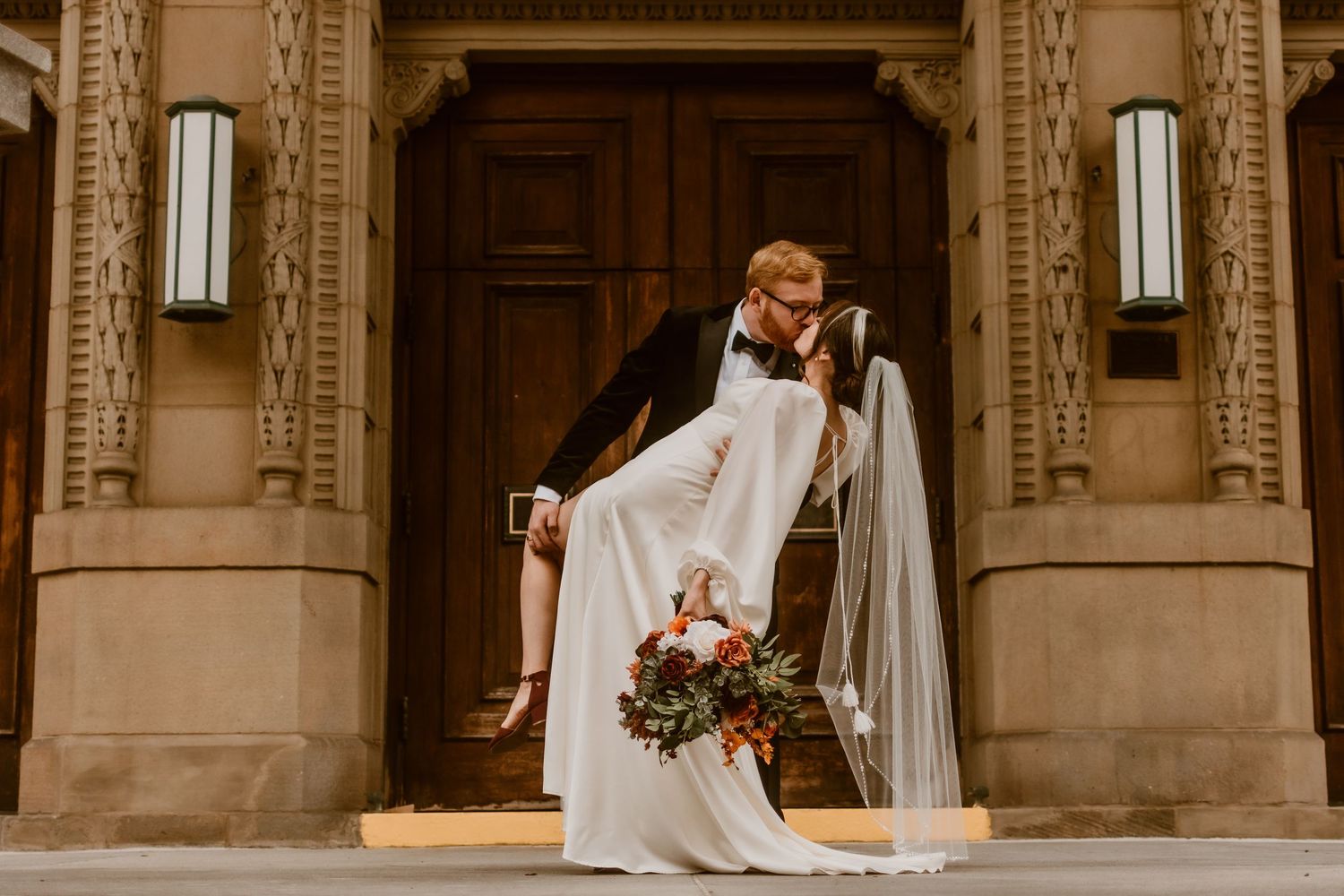 A newlywed couple exits through an elegant stone archway after their ceremony.