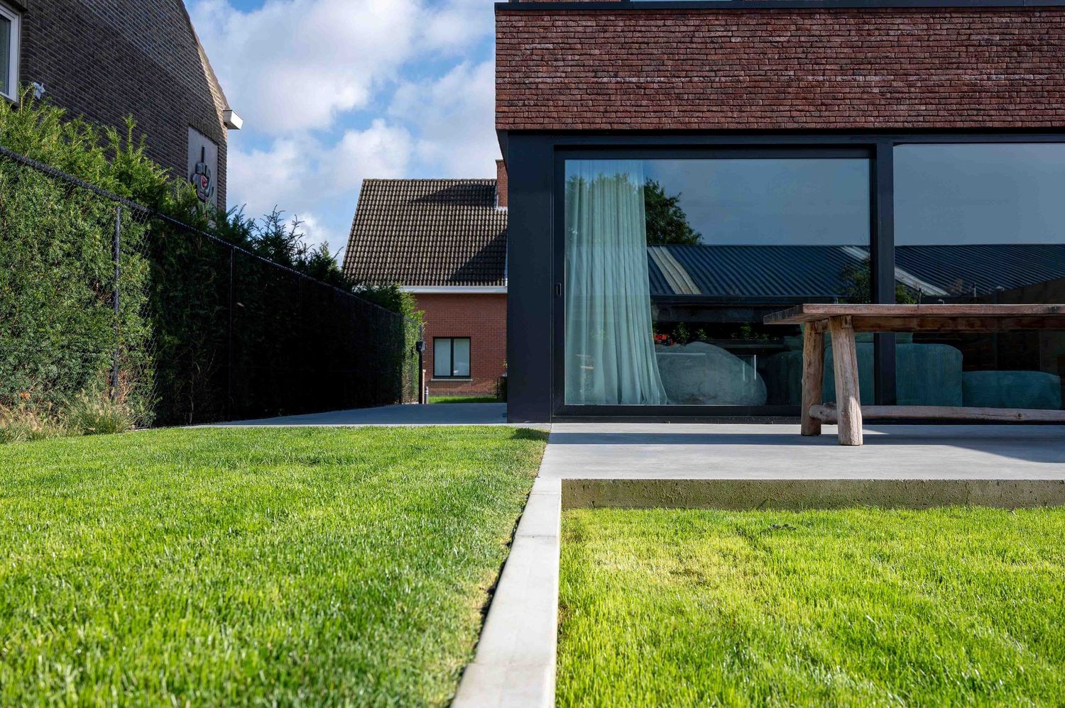 Garden view through glass windows with brick exterior and landscaped greenery.