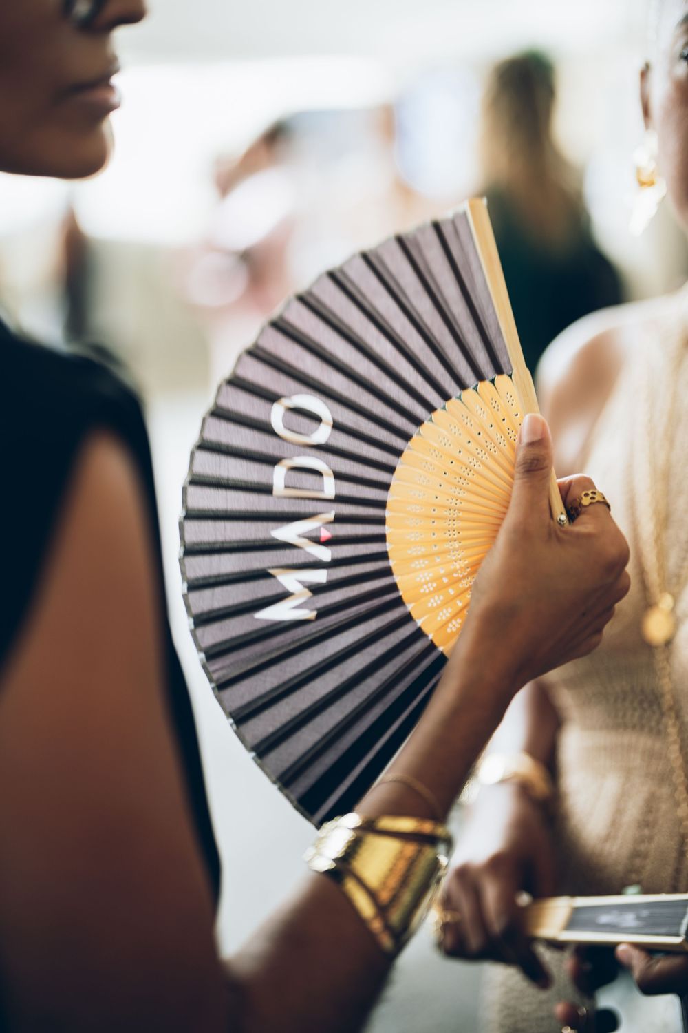 A series of photos showing a decorative hand fan in gray and orange colors being held at different angles.