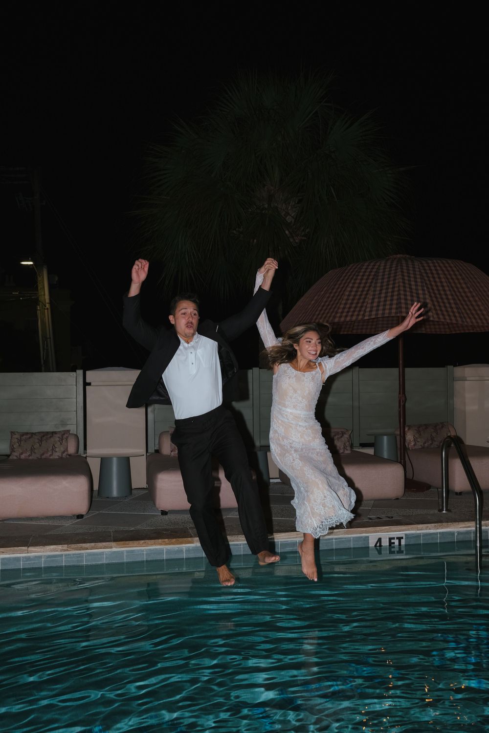 Happy married couple jumping in pool