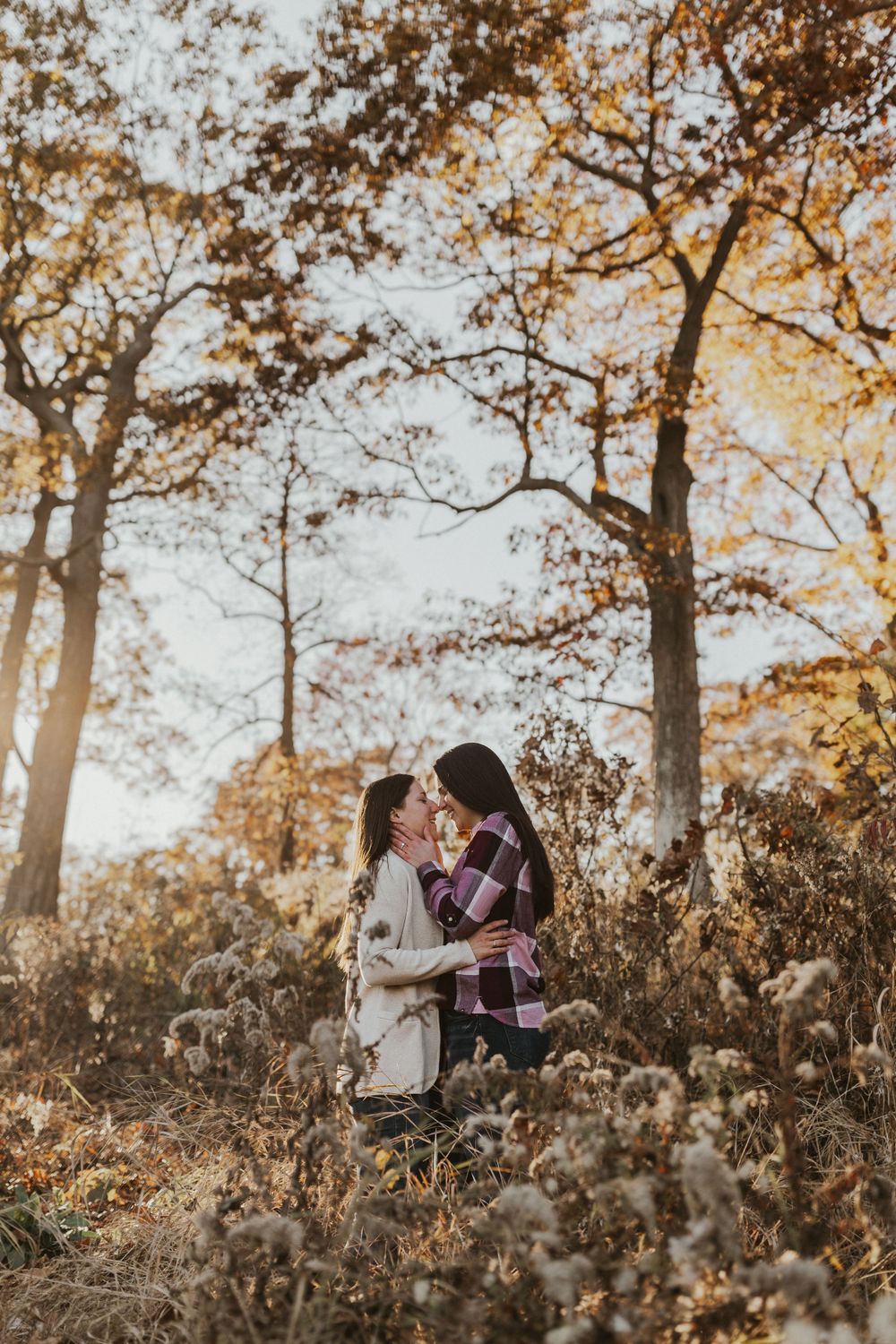 A romantic autumn photography session in a wooded area with golden sunlight filtering through the trees.