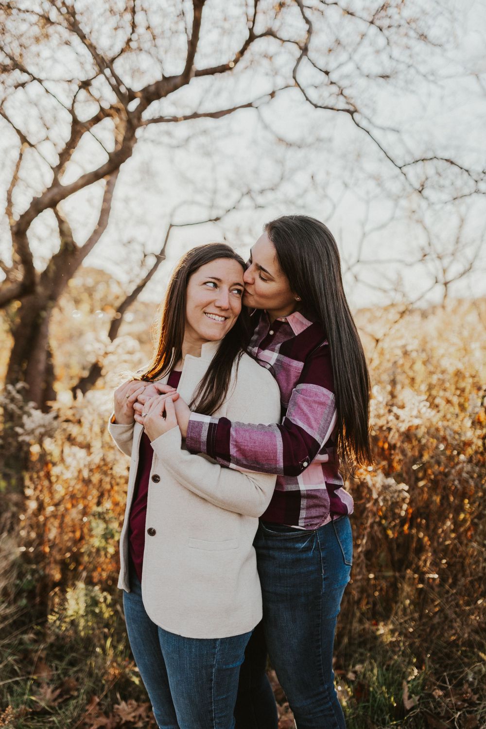 A couple sharing an intimate moment outdoors during a fall photo session with warm lighting.