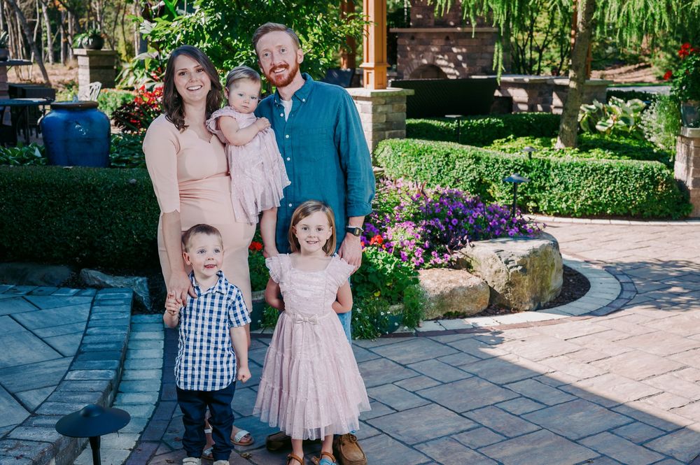 Family of five posing in a colorful garden with two parents and three young children.