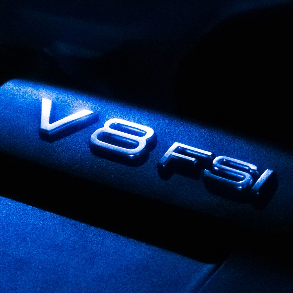 Close-up macro shots of blue illuminated V8 badges on a vehicle showing progressive detail and lighting angles.