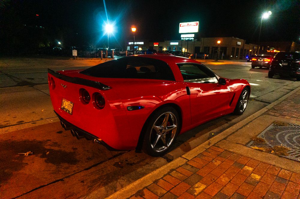 Red Corvette sports car photographed at night under street lights showing multiple angles and reflections.