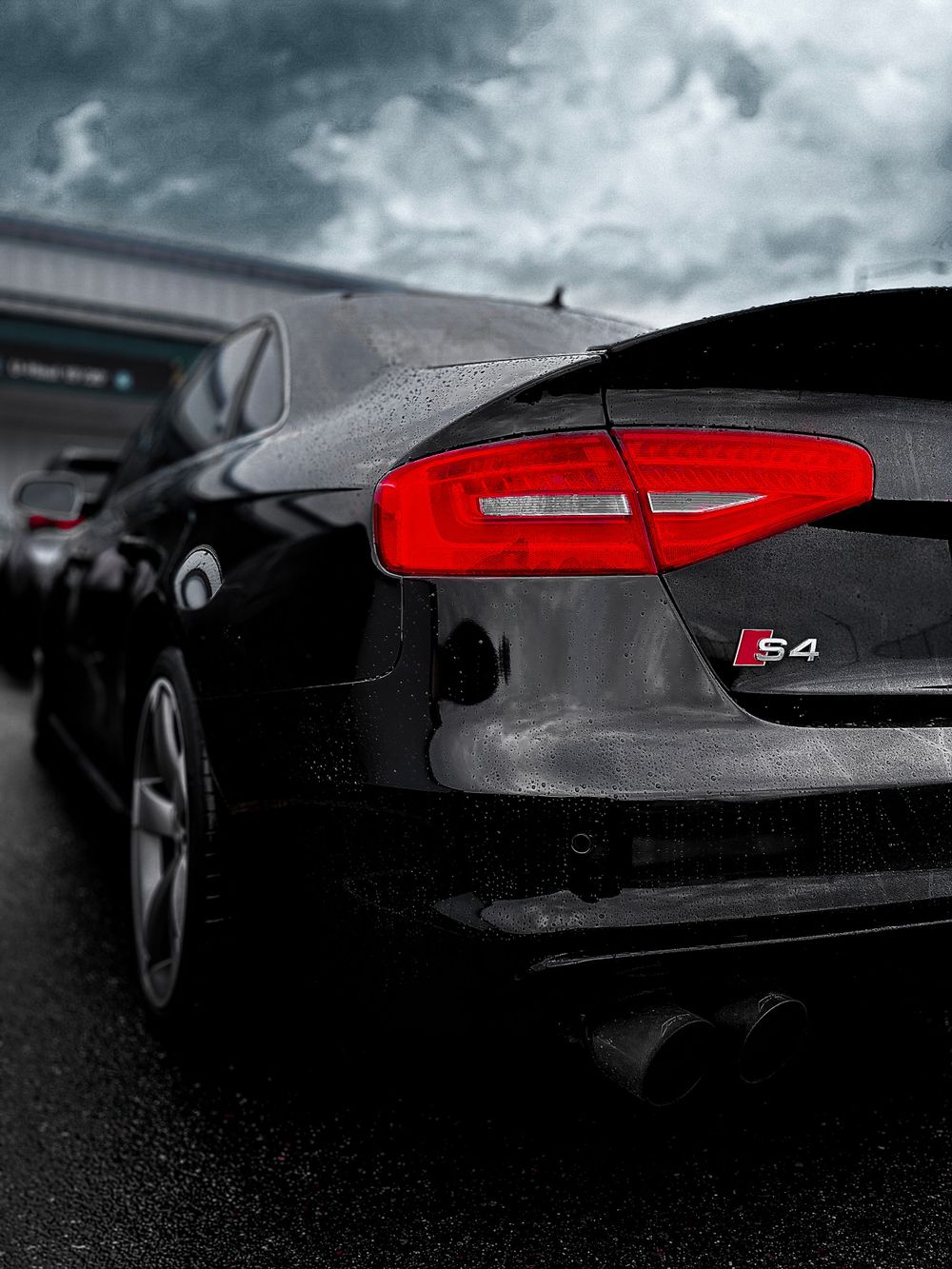 Close-up shots of a black Audi S4's rear taillights and badging in dramatic lighting.