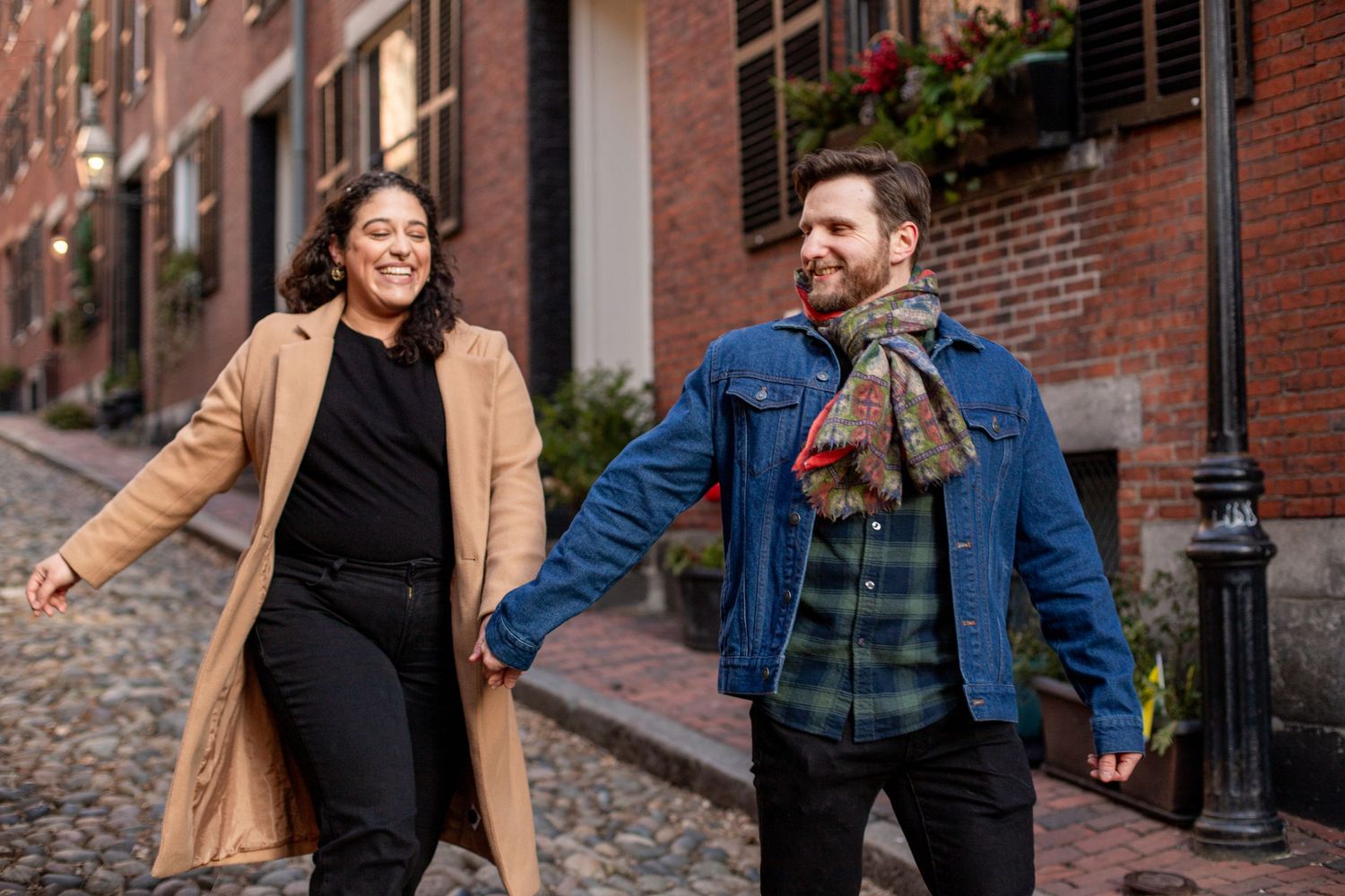 couple smiles together for photo in historic beacon hill boston acorn street in beacon hill