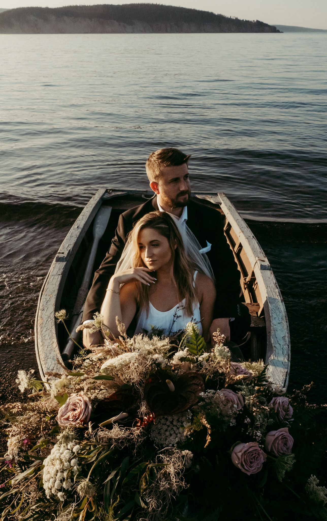 A romantic boat scene with flowers and a couple sitting together on calm waters at sunset.