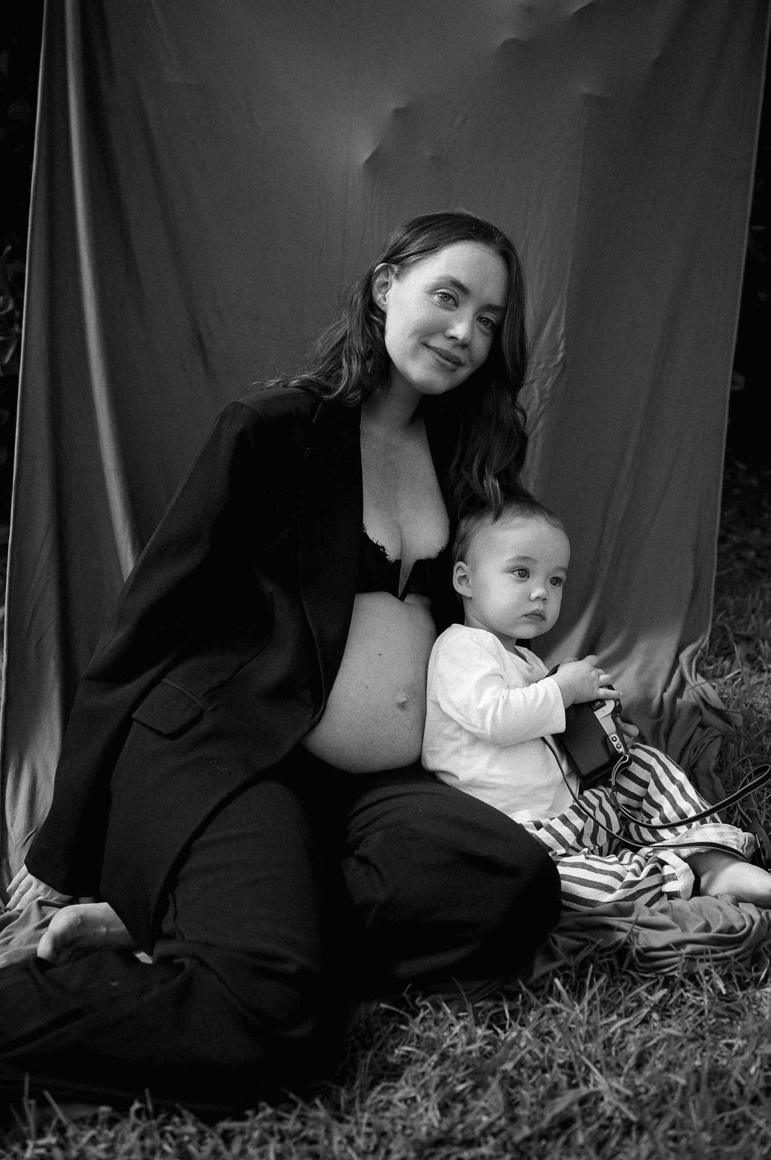 A tender moment captured in soft light as a parent cradles a newborn baby next to a tall mirror.