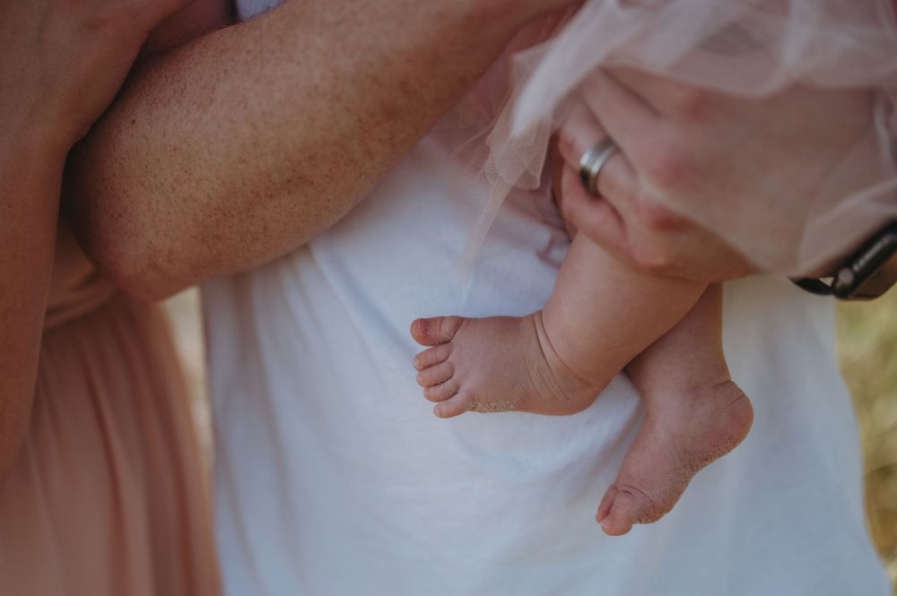 Close-up of tiny baby feet being held against white fabric.