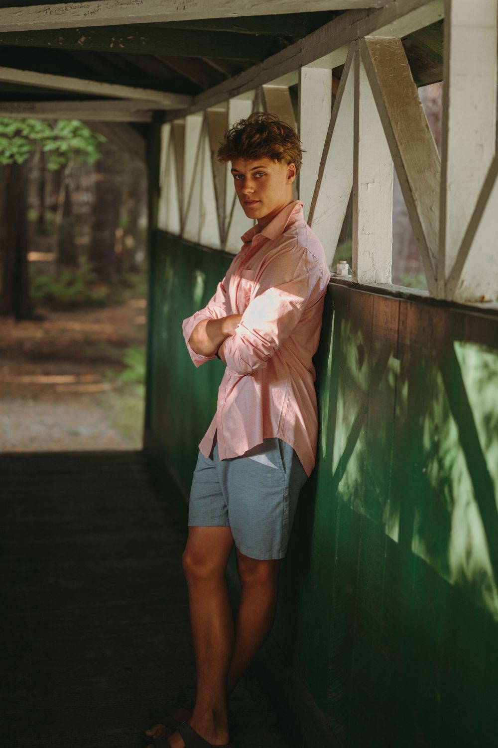 A casual portrait in a covered bridge with natural lighting and wooden architectural details.