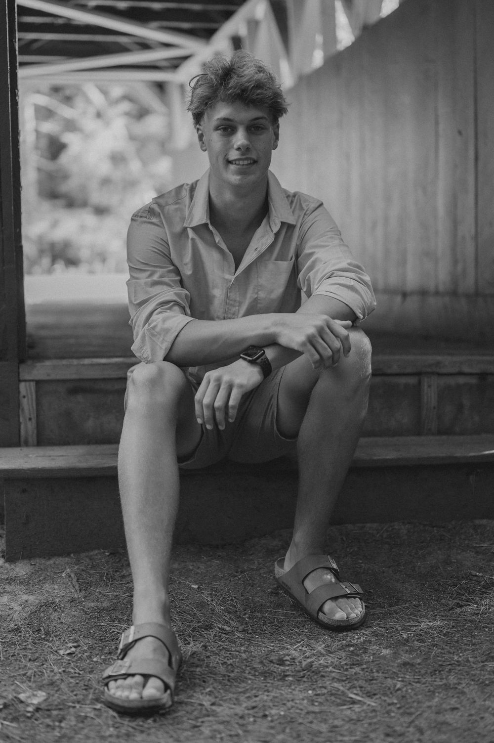 A black and white portrait on a wooden bench showcasing casual summer style.