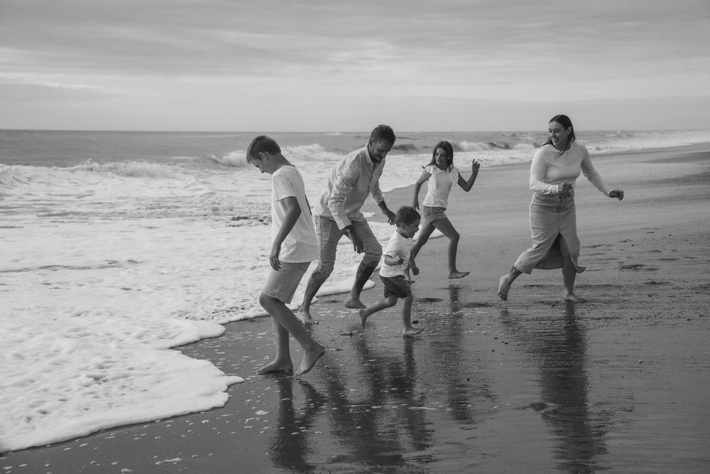 family running away from waves on beach