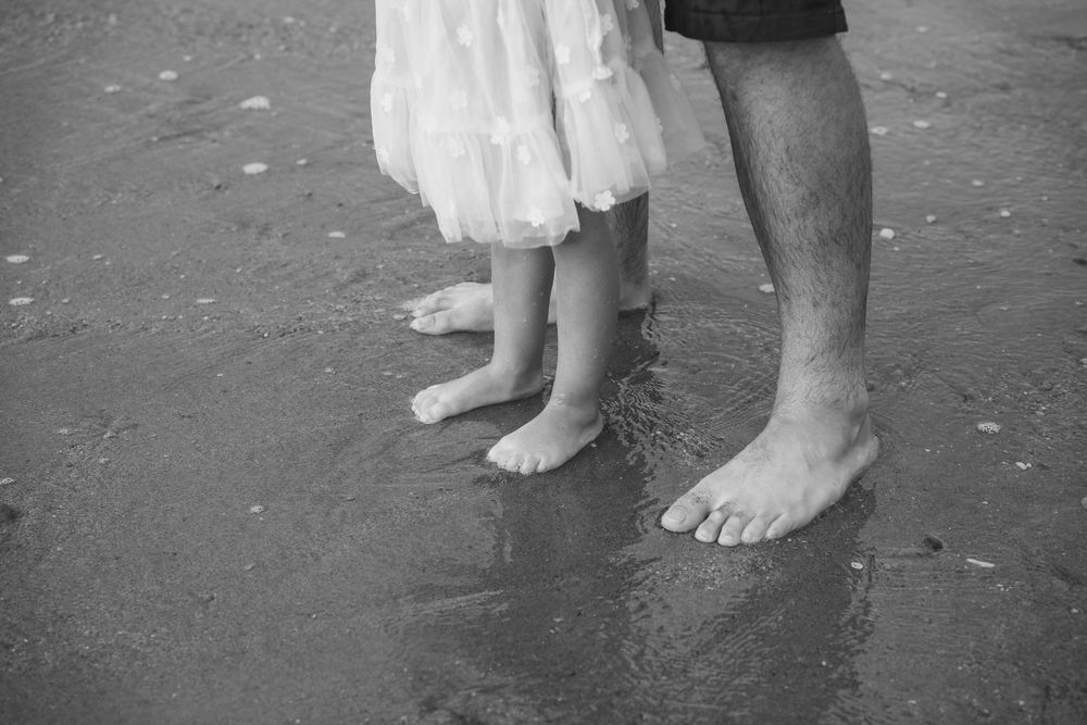close up of Dad and daughters feet at the beach