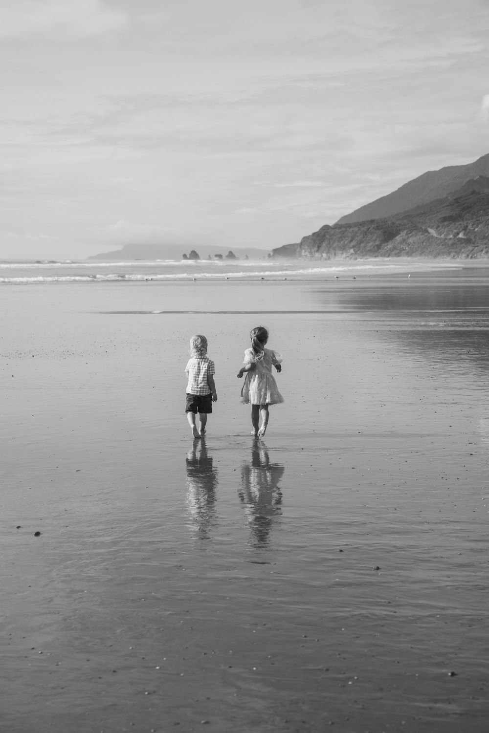 two young siblings running together at Rapahoe Beach