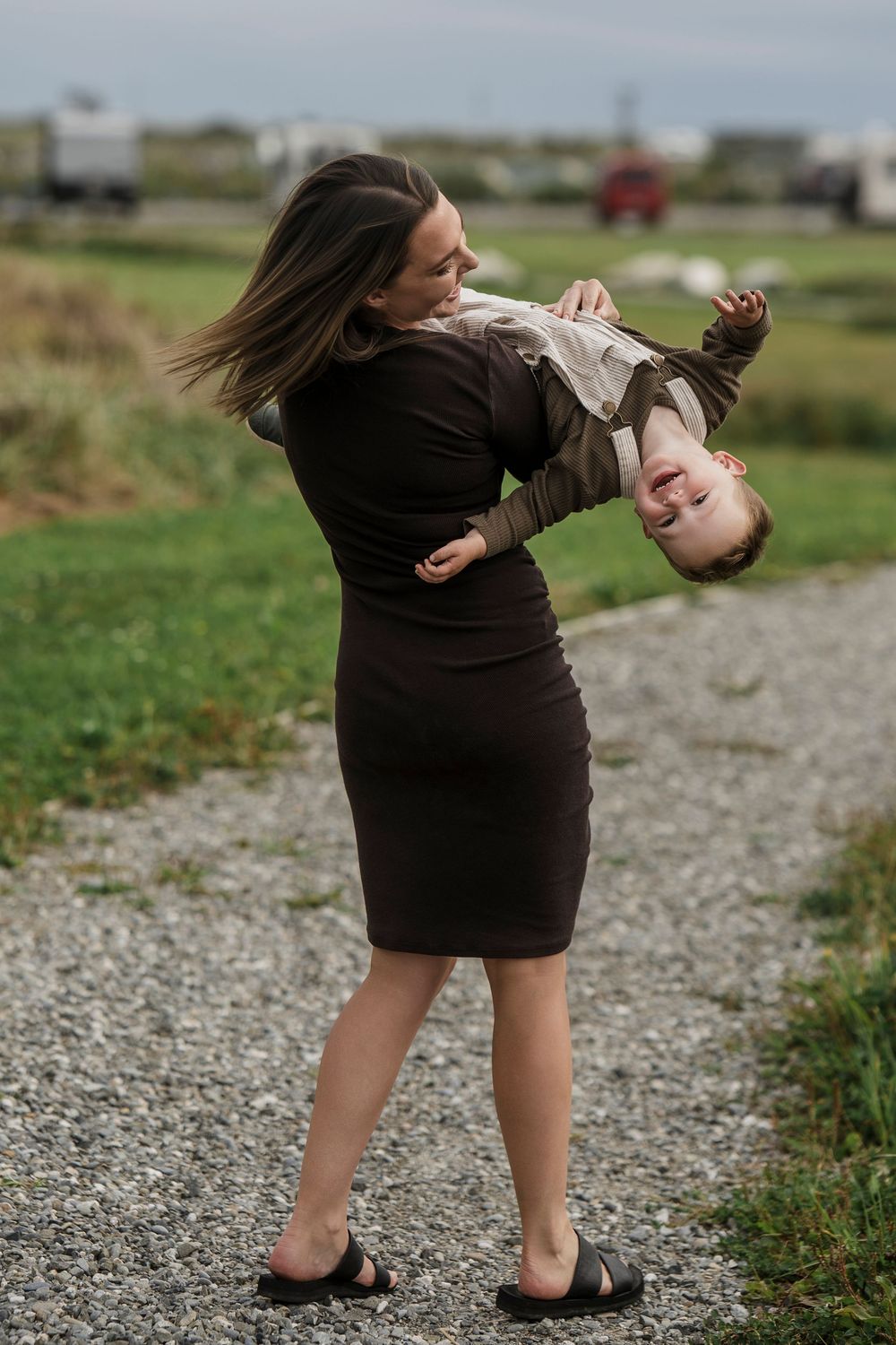 mother holding toddler son upside down walking laughing