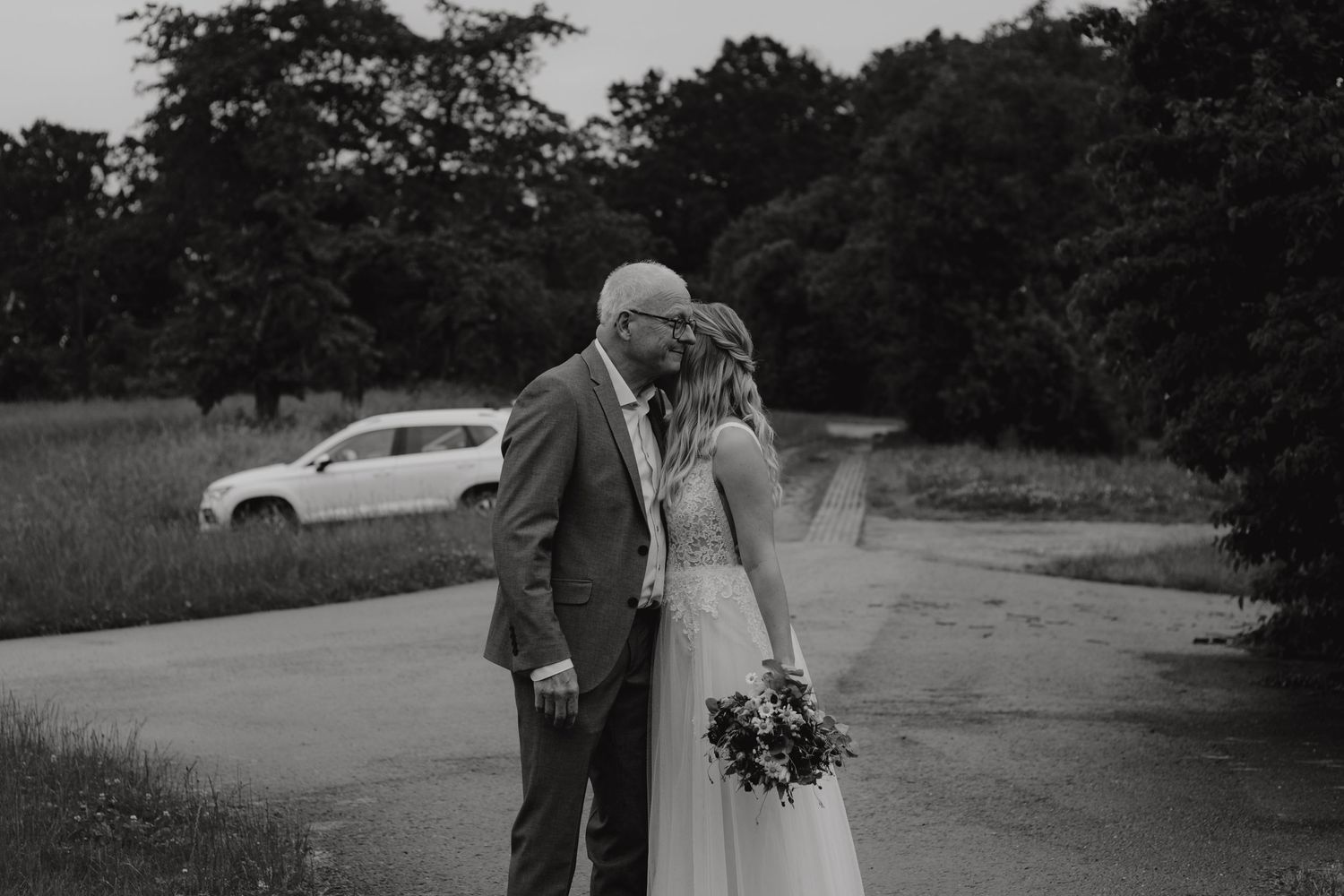 Black and white portrait of a couple sharing an intimate moment in a parking lot.