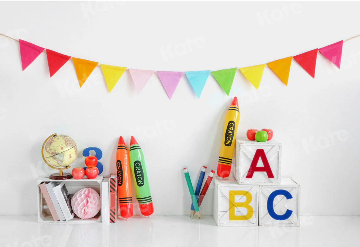 Colorful bunting flags hang above educational toys including ABC blocks, oversized crayons, and classroom decorations on white shelf.