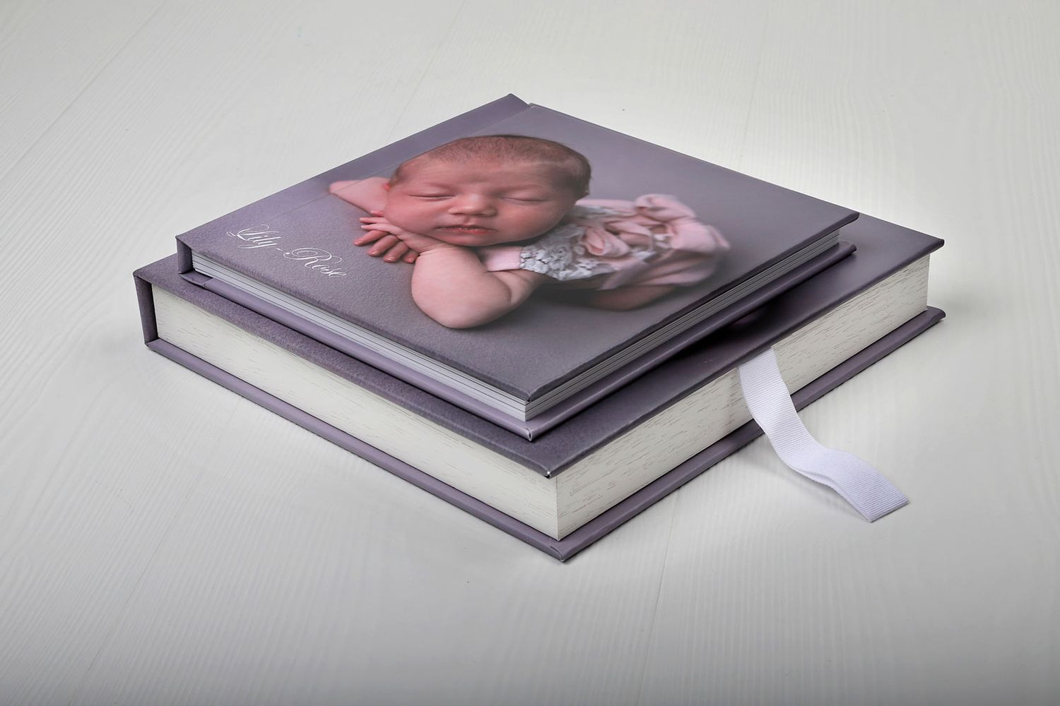 Pile d'albums photo professionnels avec une couverture grise et un marque-page en ruban blanc.