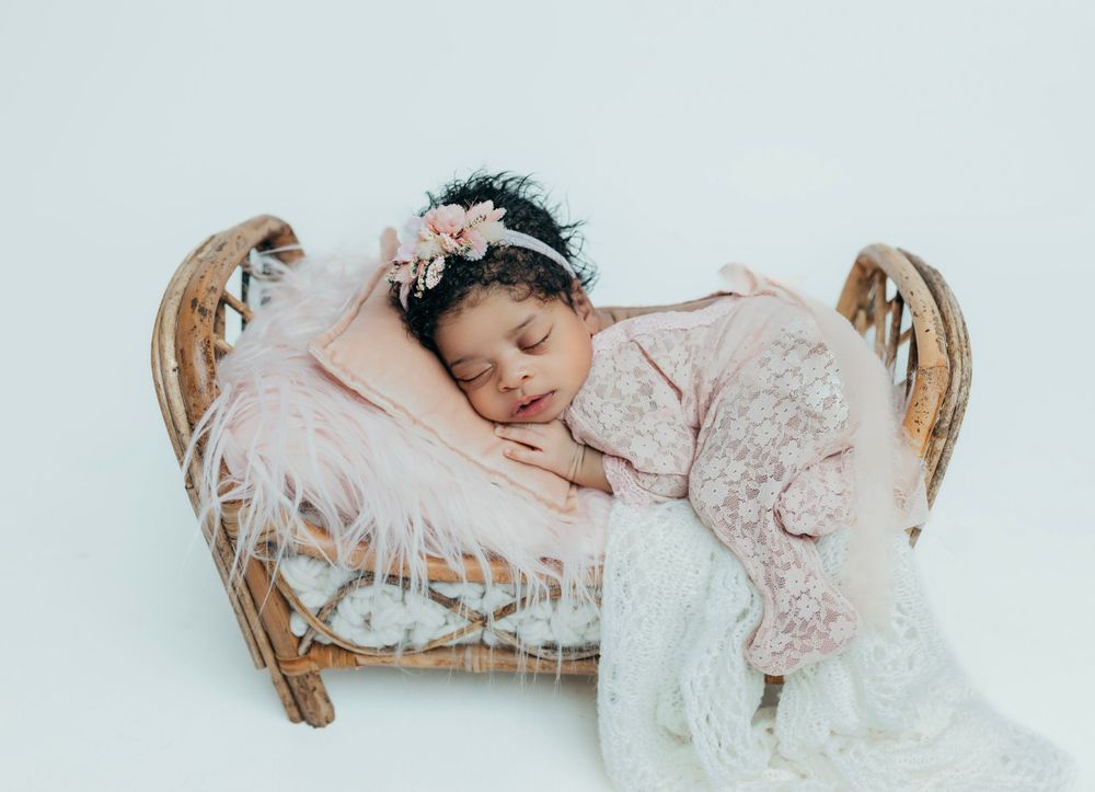 Newborn baby sleeping peacefully in antique basket with delicate lace details.