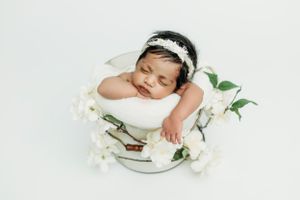 Elegant newborn photography set featuring white floral arrangements and soft lighting.