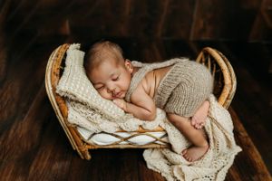 Rustic newborn photography series with baby sleeping in vintage wooden basket.