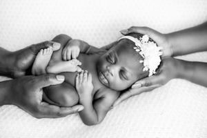 Black and white series showing gentle hands cradling sleeping newborn baby.