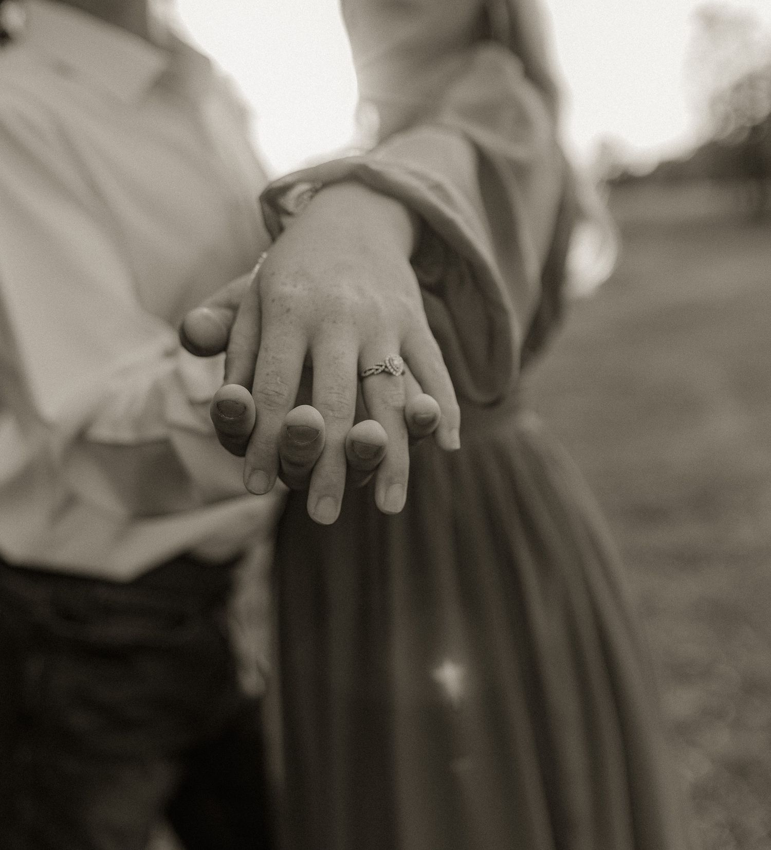 Black and white photo showing clasped hands against formal attire.